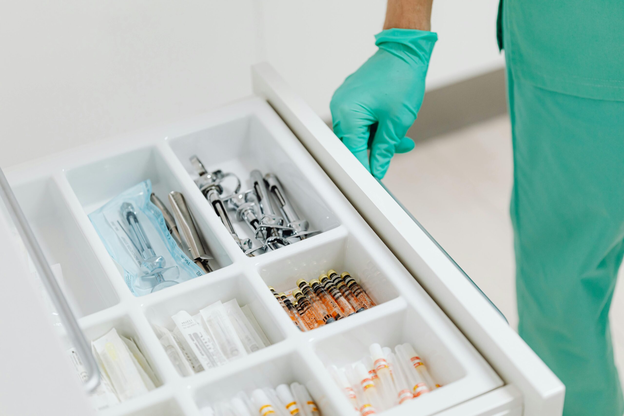 Home Sterile drawer with medical instruments and syringes in a clinic setting.